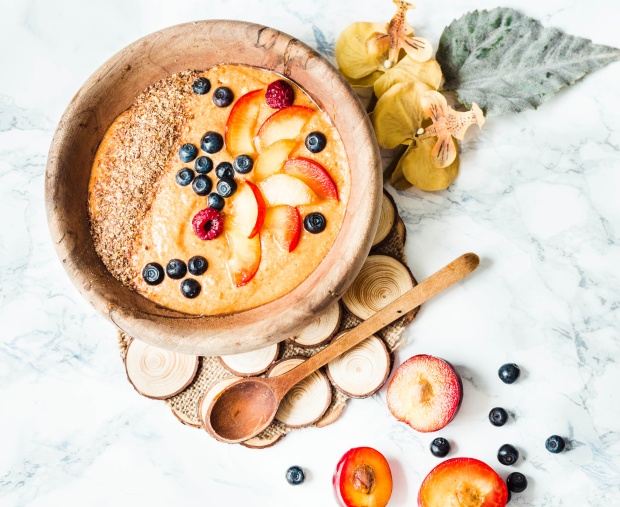smoothie bowl with peaches, plums and blueberries in a wooden di